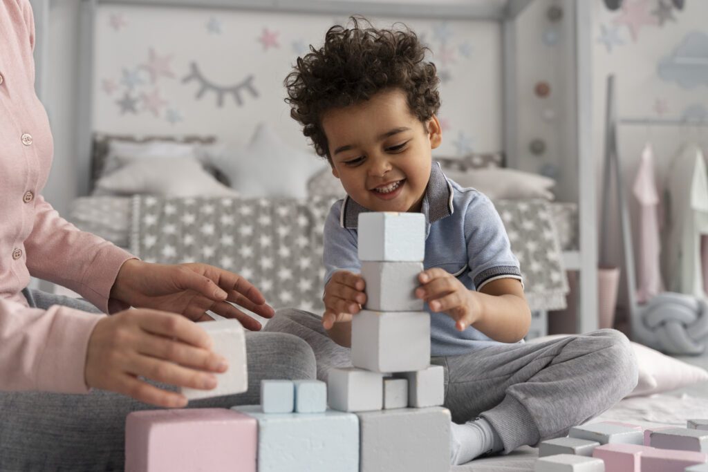 Criança feliz brincando de montar uma torre de blocos, uma atividade que ajuda a avaliar o desenvolvimento motor e cognitivo infantil durante uma consulta neuropediátrica.