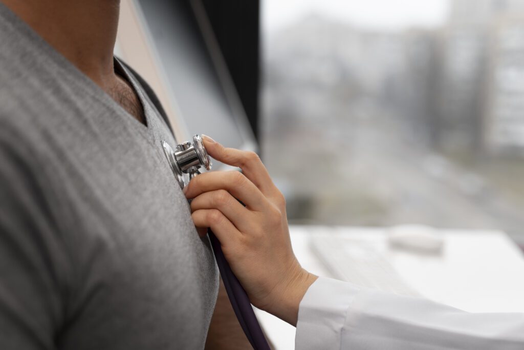 Close-up de uma cardiologista usando um estetoscópio para auscultar o coração de um paciente durante um check-up, um passo essencial para a prevenção do infarto silencioso.